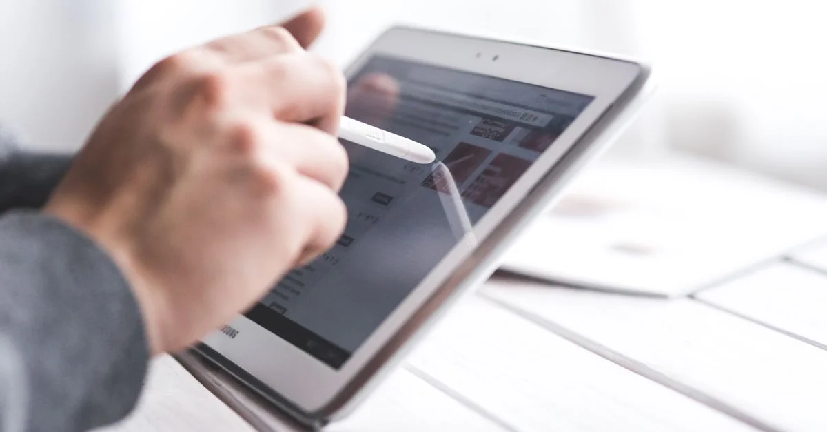 Gros plan sur une main utilisant un stylet sur une tablette, mettant en avant l'interaction avec la technologie numérique.